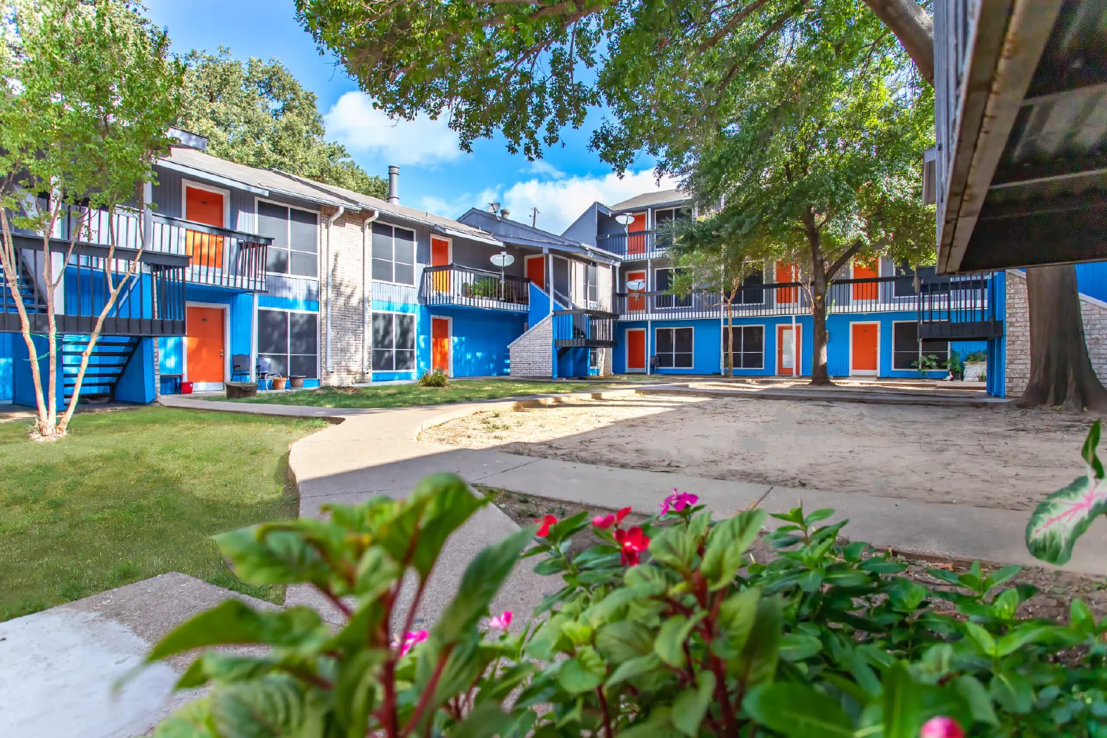 Blue and orange Villa Encanto apartment buildings around a landscaped courtyard