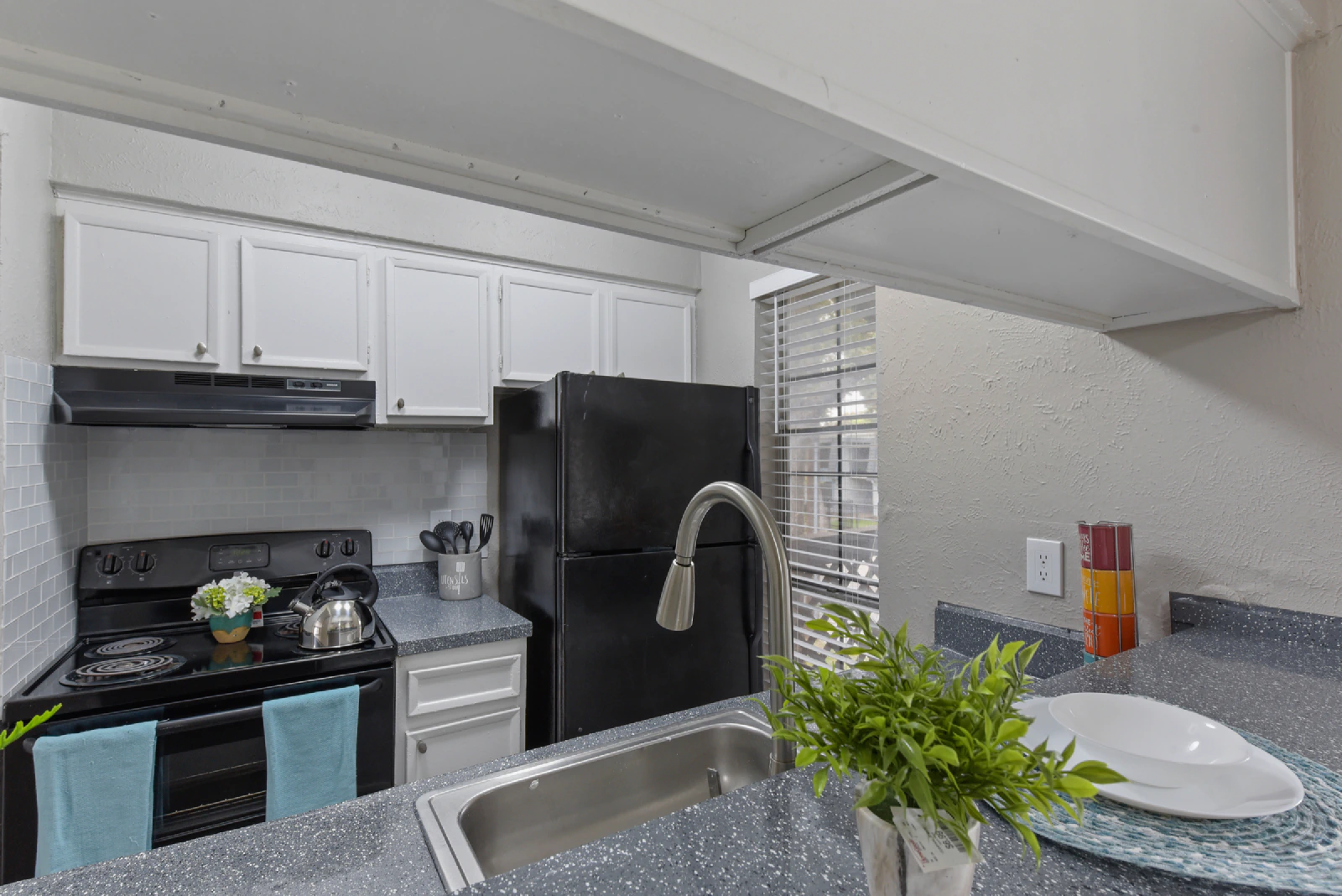 Villa Encanto kitchen with black appliances, white cabinets, and breakfast counter